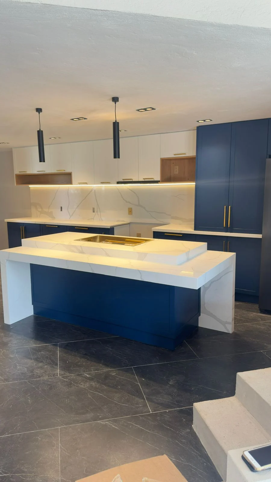 Cocina residencial con doble isla en mármol y gabinetes azul marino por Koukal Interiorismo